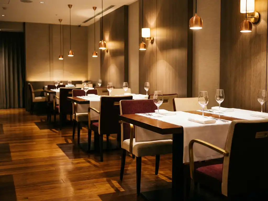 Elegant restaurant eetkamer met houten tafels, witte tafellinnen, wijnglazen en gestoffeerde stoelen onder warme hanglampen