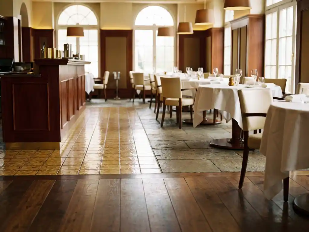 Lege restaurantzaal met verschillende vloermaterialen: gepolijst hardhout, keramische tegels en gestructureerde steen onder elegante tafels met witte tafelkleden